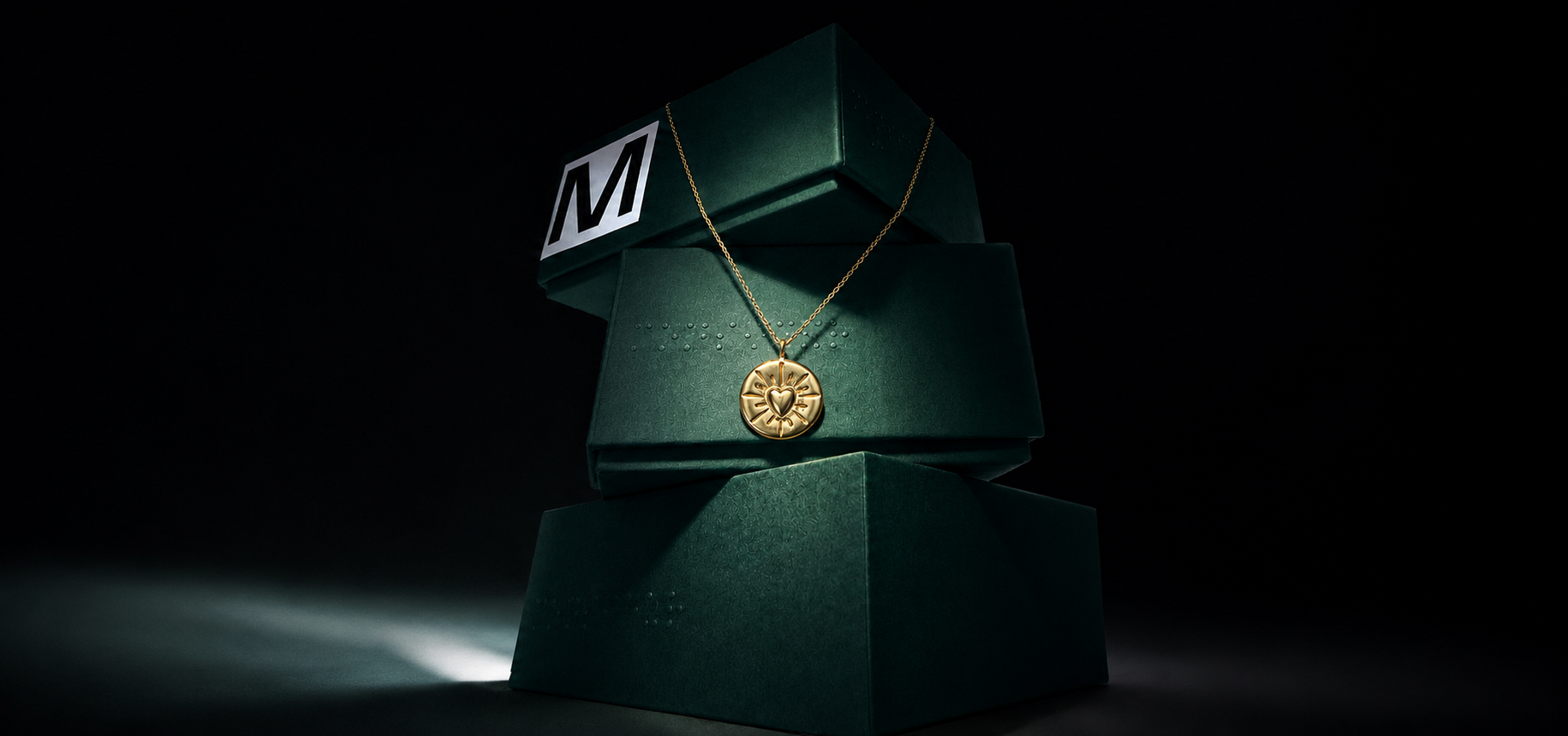 Collier médaille gravé coeur en vermeil sur une pile d'écrins Monsieur Paris